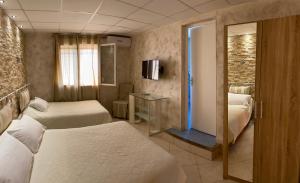 una camera d'albergo con due letti e una televisione di Hôtel Le Derby a Cagnes-sur-Mer