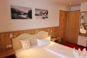 a bedroom with a white bed with wooden walls at Hotel Tirolerhof in Leutasch