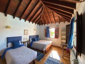 a bedroom with two beds in a room with wooden ceilings at Hotel Restaurante Bandolero in Júzcar