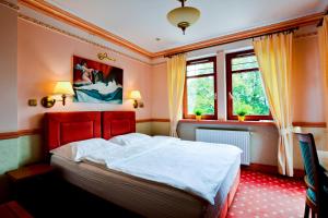 a bedroom with a bed and two windows at Willa Amor in Krynica Morska
