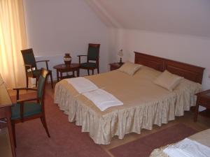 a bedroom with a large bed with chairs and tables at Várkert Panzió in Miskolc