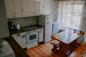 cocina con electrodomésticos blancos y mesa de madera en Viesu nams Lauciņi, en Lāde