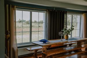 a dining room with a table and two windows at Viesu nams Lauciņi in Lāde