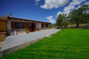 ein Haus mit grünem Rasen davor in der Unterkunft L'oliveto in Nuxis