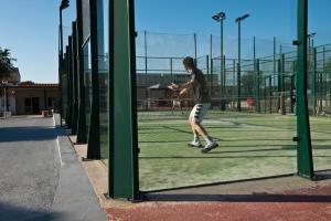 a man is playing tennis on a tennis court at Apartamentos Sa Caleta in Sa Caleta