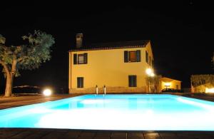 una piscina frente a una casa por la noche en LA TANA DEL CINGHIALE, en Santa Vittoria in Matenano
