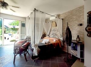 1 dormitorio con cama con dosel y silla en Poggio Mariett, en Castiglione della Pescaia