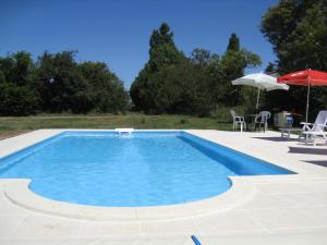 una piscina con mesa, sillas y sombrilla en La Grange, en Vanzay