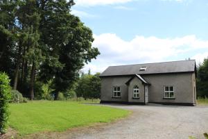 un petit bâtiment gris avec une cour herbeuse dans l'établissement Castlehamilton Cottages and Activity Centre, à Cavan