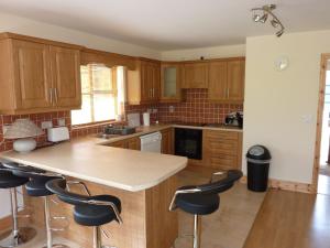 a kitchen with wooden cabinets and a island with bar stools at Castlehamilton Cottages and Activity Centre in Cavan