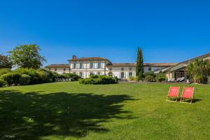 two red chairs in front of a large house at Bordeaux-Blaye-St-Emilion-Arcachon-Domaine de Cézac in Cézac