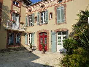 ein Haus mit einer roten Tür und Fenstern in der Unterkunft Chambre d'Hôtes Bastide du Cosset in Barcelonne-du-Gers