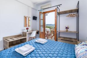 a bedroom with a blue bed and a balcony at Nepheles in Skopelos Town