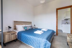 a bedroom with a bed with a blue comforter at Nepheles in Skopelos Town