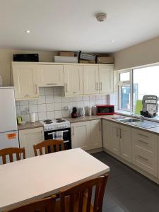 a kitchen with white cabinets and a table with chairs at The Comfy Cottage in Swords