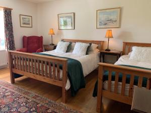 a bedroom with two beds and a red chair at The Mill in Dunfanaghy