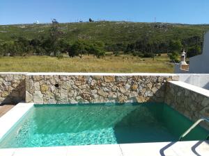 una piscina con una pared de piedra y agua azul en Pro Touristic Montejunto Villas, en Arieiro