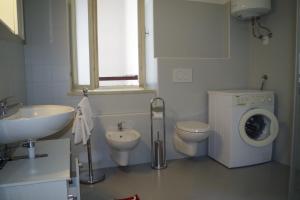 a bathroom with a toilet sink and a washing machine at Da Francesca in Fiera di Primiero