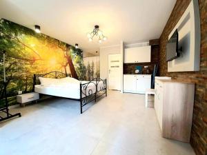 a bedroom with a bed and a kitchen at Apartamenty w Puszczy in Augustów