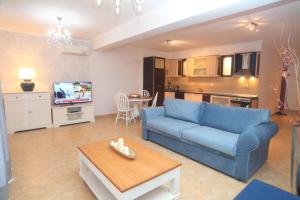 a living room with a blue couch and a table at Pirofani Villa Apartments in Apolpaina