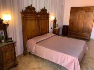 um quarto com uma cama e uma cabeceira em madeira em Palazzo Gentilizio de Maffutiis em Auletta
