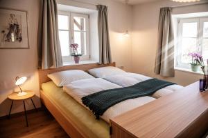 ein Bett in einem Schlafzimmer mit zwei Fenstern in der Unterkunft Puenlandhof in Bruneck