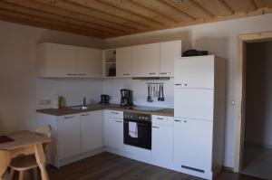 eine Küche mit weißen Schränken und einem weißen Kühlschrank in der Unterkunft Haus Stückler in Steinbach am Attersee