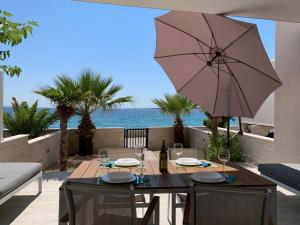a patio with a table with an umbrella and the ocean at Apartment GARDEN in Mandre