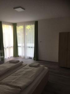 a bedroom with two beds and a large window at Apartmanhotel Baraton*** in Balatonfüred