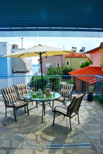 una mesa con sillas y una sombrilla en el patio en Blue Wave, en Palaión Tsiflíkion