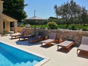 a pool with chairs and an umbrella next to a retaining wall at VILLA STELLA JURICANI in Umag