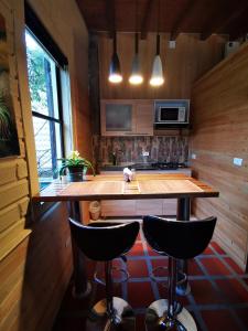 a kitchen with a large wooden table and two bar stools at CABAÑAS MONTEVERDE - Guarne ANT in Guarne