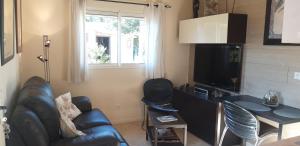 een woonkamer met een bank, een tafel en een televisie bij Lou Bagnou Mi-Clos in Bagnols-sur-Cèze