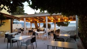 un restaurante al aire libre con mesas y sillas y el océano en Apartments & Rooms Baltazar, en Podstrana