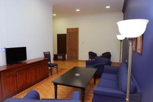 Araks Hotel Complex في غيومري: غرفة معيشة مع كراسي زرقاء وطاولة وتلفزيون