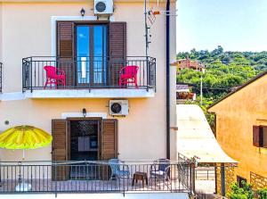un balcone di un edificio con sedie rosse e ombrellone di Marihome a Caprioli