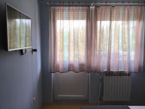 Habitación con ventana con cortinas rosas y radiador en Bingo Apartments, en Banja Luka