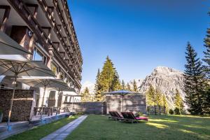 um pátio com cadeiras e guarda-sóis em frente a um edifício em Blatter's Arosa Hotel & Bella Vista SPA em Arosa