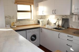 uma cozinha com um lavatório e uma máquina de lavar roupa em Beach front apartment 1 em Sagres