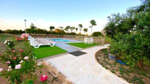 un patio trasero con piscina, banco y flores en CAN DAMIA 1, en Cala Saona