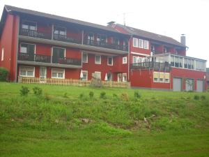 un edificio rojo con un campo verde delante de él en Hotel Europa, en Holsthum