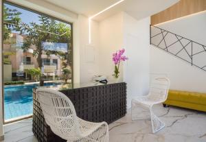 カト・ダラトソにあるLotus Hotel Apartmentsのスイミングプール付きの客室内の白い椅子2脚