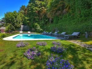 una piscina en un patio con flores púrpuras en Domus Plinii 1792 Suites, en Faggeto Lario 