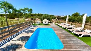 a pool with lounge chairs and a wooden bridge at CAN DAMIA 2 in Cala Saona