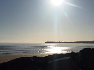 a beach with the sun shining over the water at Sunny Hill View in Lahinch +4 photos