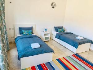 een slaapkamer met 2 bedden en een tapijt bij Sifa Getaway in Muscat