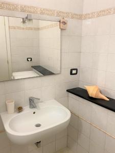 Baño blanco con lavabo y espejo en Le case della Lizza - Casa Blu, en Levanto