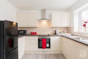 una cocina con armarios blancos y una toalla roja en el horno en Birmingham Estate - Contractor & Group Accommodation - Secure Parking en Birmingham