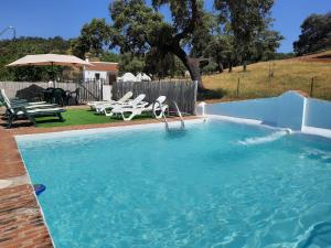 a large swimming pool with chairs and a table at CASA RURAL LA DEHESILLA in Cazalla de la Sierra