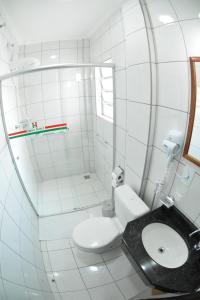 uma casa de banho branca com um WC e um espelho. em Itália Hotel em Telêmaco Borba